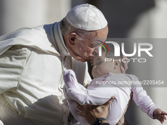 Pope Francis kisses a baby as he arrives to celebrate his Weekly General Audience in St. Peter's Square in Vatican City, Vatican on Septembe...