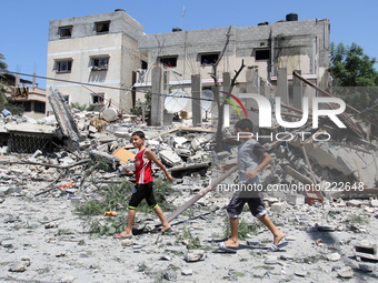Palestinian boys walk next to the rubble of house destroyed after Israeli air strikes in Gaza City, 23 August 2014. (