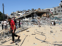 Palestinians next to the rubble of house destroyed after Israeli air strikes in Gaza City, 23 August 2014. (
