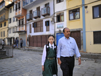 Formal Living Goddess Kumari MATINA SHAKYA in a school uniform along with her Father walks towards school on her first day at Kathmandu, Nep...