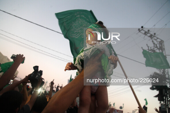 A Palestinian waves a Hamas flag (R) as others celebrate what they said was a victory over Israel, following a ceasefire in Gaza City August...
