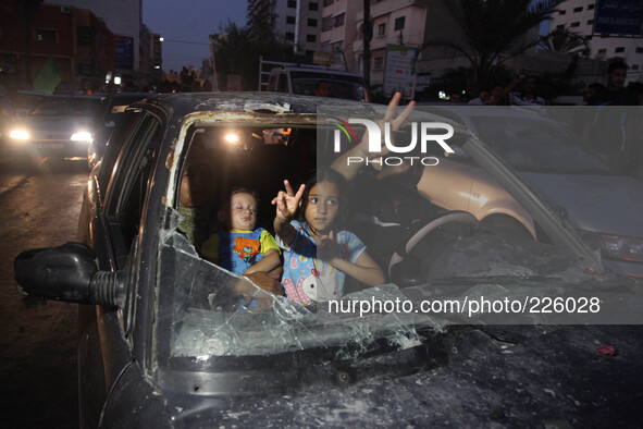 Palestinians ride in a damaged car as they celebrate with others what they said was a victory over Israel, following a ceasefire in Gaza Cit...
