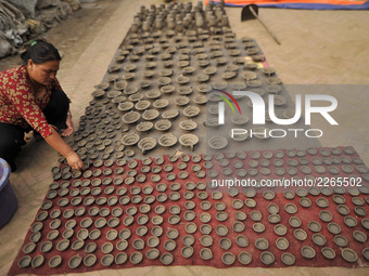 A woman arranging clay pot lamps, being sun dried for upcoming Tihar or Deepawali Festival on his workshop at Pottery Square, Bhaktapur, Nep...