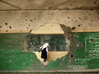A Palestinian student Writing on the blackboard  inside a classroom that witnesses said was shelled by Israel during its offensive, on the s...
