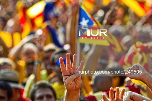 National Day of Catalonia, a demonstrator does the symbol of the four bars of the Catalan flag, that symbolize Catalonia's independence, dur...