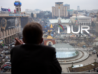 A man at his balcony watches people take part in a mass rally on Independence square in Kiev, on February 16, 2014. Ukraine's political situ...
