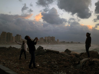 A view shows buildings during Palestinian man picks up a picture of his friend on the shore of the sea in Gaza City, which is experiencing l...