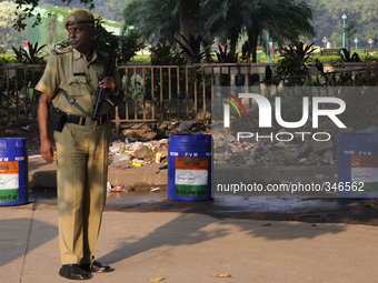 A cop with automatic weapons standing in front of the trash bins during Clean India Campaign in Kolkata, India.
 (