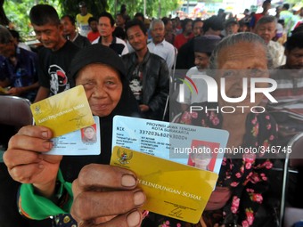 SURAKARTA, INDONESIA - November 21 : Poor peoples shows the social fund card during queued to take subsidized fuel compensation funds amount...