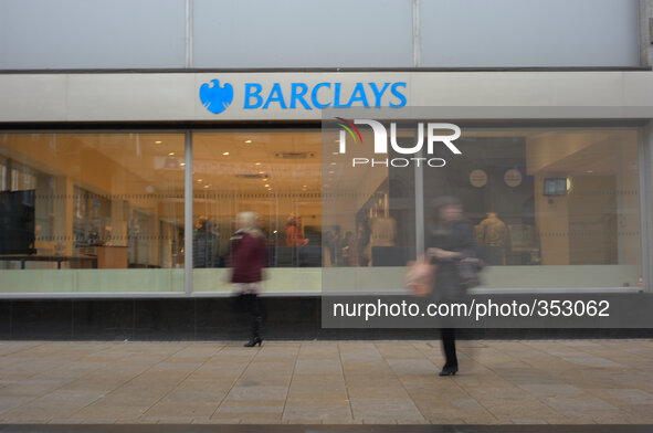 A branch of Barclays emmitting light as people walk by. National and international banks and building societies, in the UK, who lend mortgag...