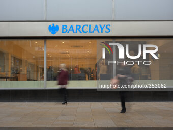 A branch of Barclays emmitting light as people walk by. National and international banks and building societies, in the UK, who lend mortgag...