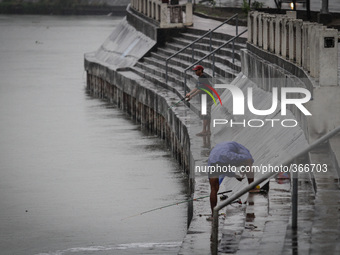 Makati City, Philippines - Men fish by the river in Makati City despite warnings from local government officials as Typhoon Hagupit (locally...