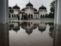 The people of Aceh enjoy the atmosphere around the Mosque Baiturrahman left when the tsunami hit a decade ago in Banda Aceh, capital of Aceh...