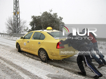 Palestinians push a car on a street during a snow storm in the West Bank city of Ramallah January 7, 2015. A storm buffeted the Middle East...