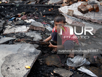 A boy was searching for charcoal in the remains of the gutted things in Poolpar Slum, Dhaka, Bangladesh on January 13, 2015. (