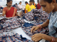 A seamstress removing threads from clothing destined for the US market at a garment factory in Bangalore. Many of the workers emigrate from...