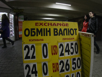 People passes the currencies exchange rate plate downtown Kiev. Ukraine's hryvnia plummeted 30 percent against the dollar to a new record lo...