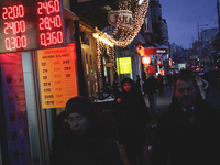 People passes the currencies exchange rate plate downtown Kiev. Ukraine's hryvnia plummeted 30 percent against the dollar to a new record lo...