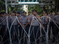 Police guard behind a barbed wire in a May Day rally in Jakarta on May 1, 2019.  Thousands of Indonesian workers are urging the government t...