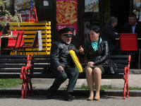 A man wearing military officer uniform talk to a woman sitting on a bench at Khreshchatyk street as warm spring weather comes in Kyiv, Ukrai...