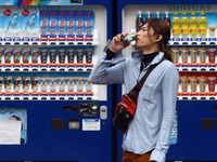 People purchase bottle drinks from a vending machine on  Feb. 12, 2015 in Tokyo, Japan. Around half of the vending machines in Japan sell dr...