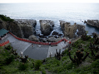 Path with bright red fence is leading to the cave where is Udo Jingu Shrine, the cave is on the edge of cliff overlooking the ocean  in Miya...