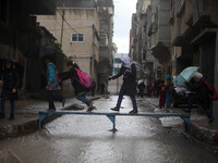 Palestinian girls walk on a makeshift iron bridge over floodwaters in Shati refugee camp during a rain storm in Gaza City, Thursday, Feb. 19...