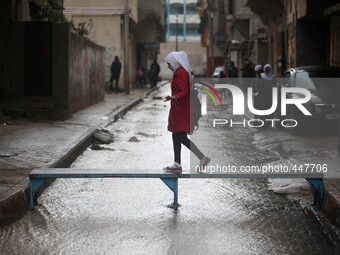 A Palestinian girl walk on a makeshift iron bridge over floodwaters in Shati refugee camp during a rain storm in Gaza City, Thursday, Feb. 1...
