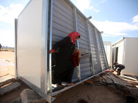 A Palestinian woman Inspects a container as a temporary replacement for their house that was destroyed by what they said was Israeli shellin...