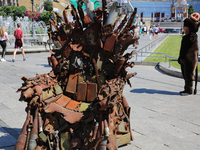 A street entertainer dressed in the Pumbaa costume looks at the iron Throne installed at Independence Square in Kyiv,  Ukraine,  June 25, 20...
