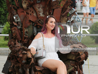 A woman poses for a picture sitting on iron Throne installed at Independence Square in Kyiv,  Ukraine, June 28, 2019. 