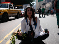 An activist with plants in her hands sits in the middle of a street during a rally in favor of the creation of the 'Augusta Park', after bei...