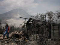 In this photo taken on March 7, 2015, A resident saw houses that lay in ruins as a result of a series of volcanic eruptions of Mount Sinabun...