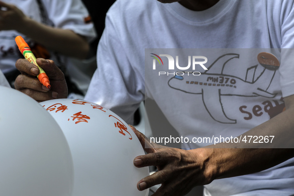 A man writes a message on a balloon for the missing Malaysian Airlines MH370 during the Day of Remembrance for MH370 in Kuala Lumpur, Malays...