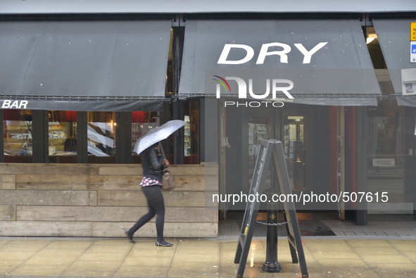 A person sheltering underneath an umbrella, due to the heavy rain, on Monday 30th March 2015. 