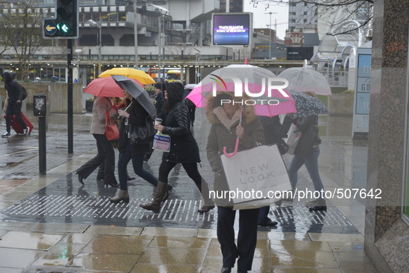 People sheltering underneath umbrellas, due to the heavy rain, on Monday 30th March 2015. 