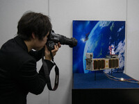 Member of the media take photograph of the miniature satellites payload comprise two of Japans most popular animated characters  Mobile Suit...