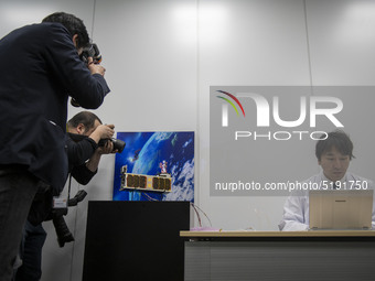 Members of the media take photograph of the miniature satellites payload comprise two of Japans most popular animated characters  Mobile Sui...