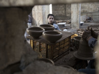 Palestinian child watching Palestinian old man creates pottery in Gaza city, April 14, 2015. (