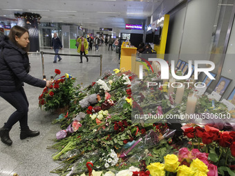 A woman lays flowers to a makeshift memorial for the crew members of the Ukrainian Boeing 737-800 plane that crashed in Iran, at the Boryspi...