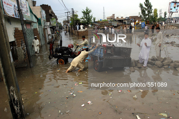 LAHORE, April 28, 2015 () -- A man pushes a vehicle in a flooded area after heavy rain in northwest Pakistan's Peshawar, April 28, 2015. At...