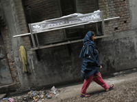 A woman walks past the dead body of Bhure Ali during his funeral in Mustafabad area of east Delhi, India on 04 March 2020. Ali, a labourer l...
