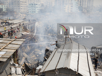 Locals help firefighters douse a fire in a slum in Mirpur, Dhaka, Bangladesh, on March 11, 2020. More than 1,000 shanties of the slum were b...