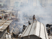 Locals help firefighters douse a fire in a slum in Mirpur, Dhaka, Bangladesh, on March 11, 2020. More than 1,000 shanties of the slum were b...