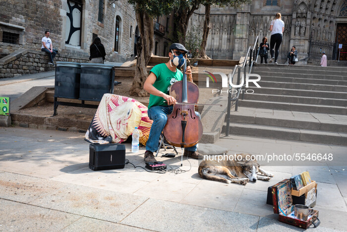 Street musician plays while he is wearing a mask in front of Barcelona Cathedral it in Barcelona, Spain, on March 14, 2020. (Photo by Adria...