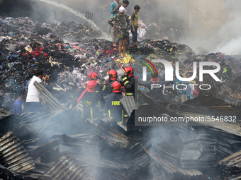 Firefighters and local people work to extinguish a fire at a Jhutpatti slum at Mirpur in Dhaka, Bangladesh, on March 14, 2020. A fire that b...