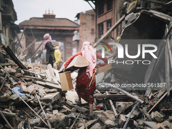 A woman carrying belongings across the rubble of a fallen building after the 2015 earthquake in Nepal., Durbar Square, Bhaktapur, Nepal - Ph...