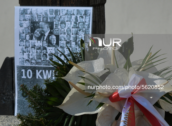A view of a poster showing photos of all passengers killed in the crash, surrounded with flowers and wreaths, seen on the day of the 10th an...