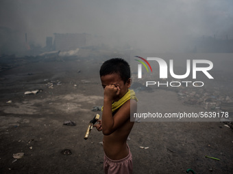 A boy covers his eyes from smoke after a fire broke out in a slum area in Tondo, Manila in the Philippines on April 18, 2020. About 500 fami...