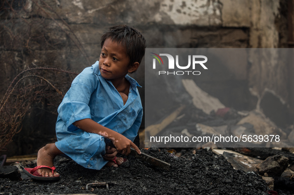 A boy collects fire debris to be sold in junk shops after a fire  broke out in a slum area in Tondo, Manila in the Philippines on April 18,...